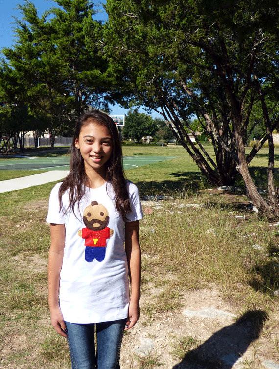 A stylish white women's t-shirt featuring unique red and blue appliqué designs and a golden necklace motif, handmade with love.