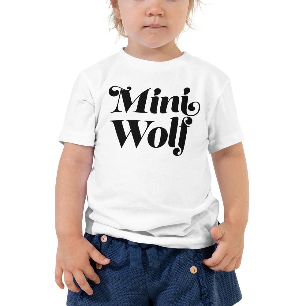 A toddler wearing a soft cotton Mini Wolf Shirt with a unique wolf print, perfect for outdoor adventures.