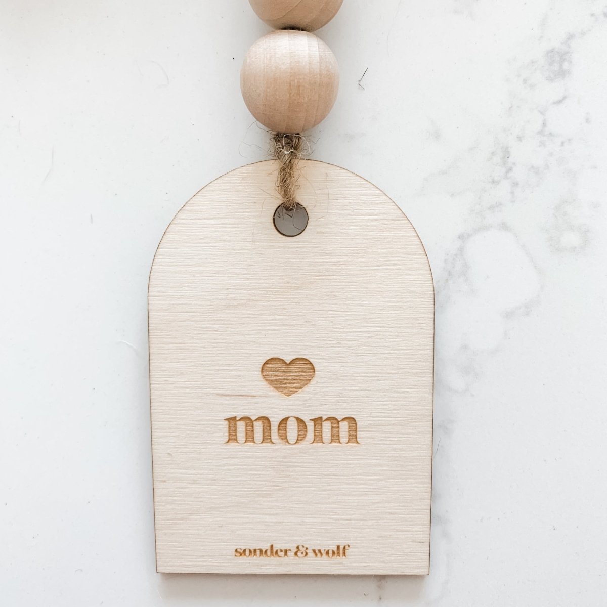 Mom Garland featuring light wood beads and a jute tassel, perfect for home decor.