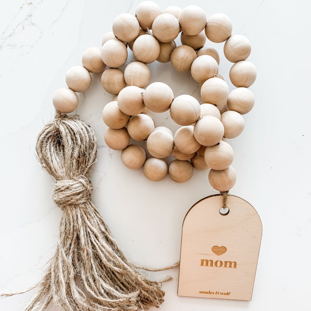 Mom Garland featuring light wood beads and a jute tassel, perfect for home decor.