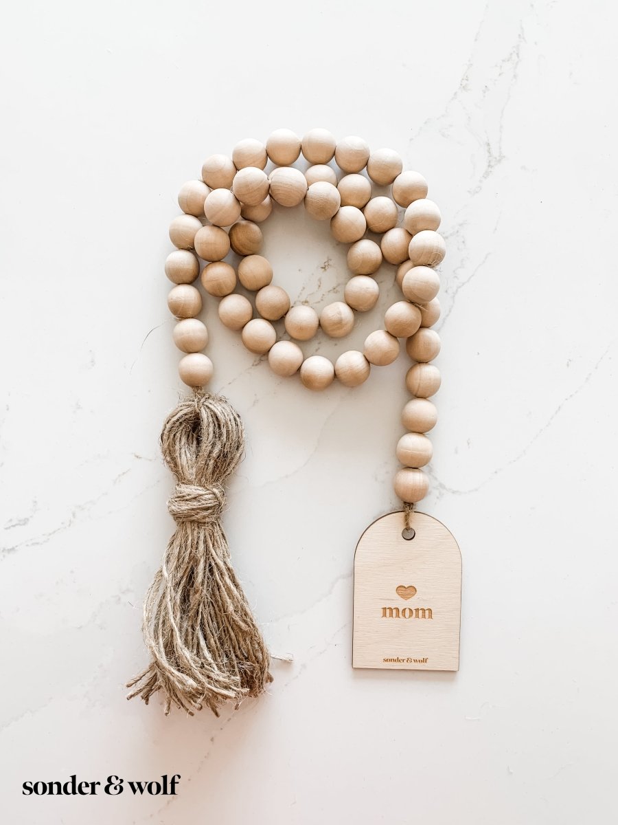 Mom Garland featuring light wood beads and a jute tassel, perfect for home decor.