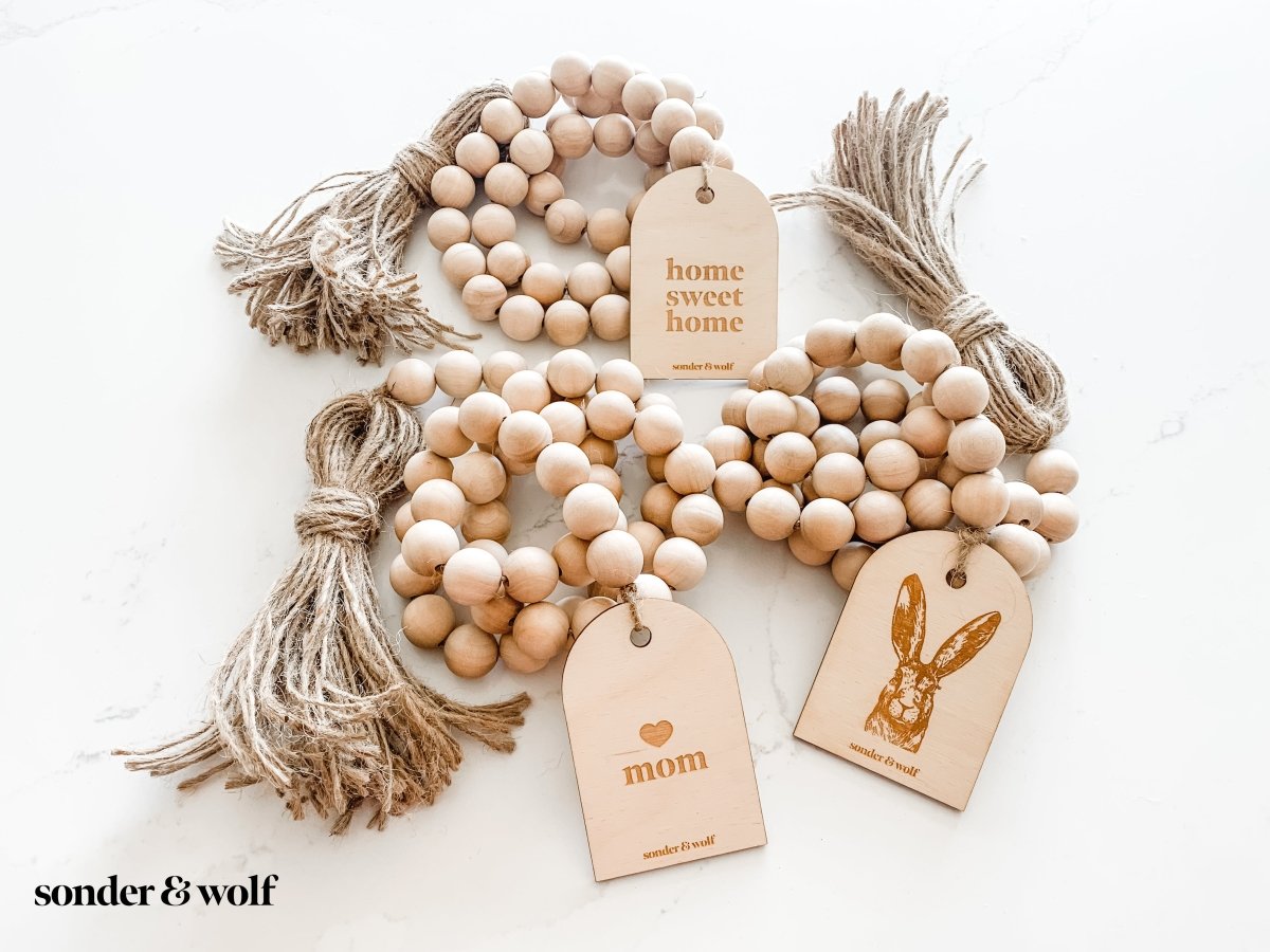 Mom Garland featuring light wood beads and a jute tassel, perfect for home decor.