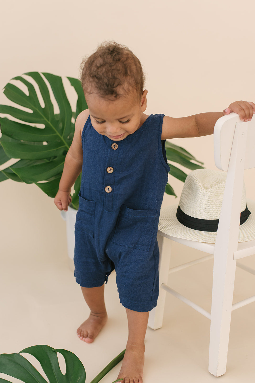 A stylish navy crop linen romper for babies, featuring diaper snaps and a comfortable fit, perfect for various occasions.