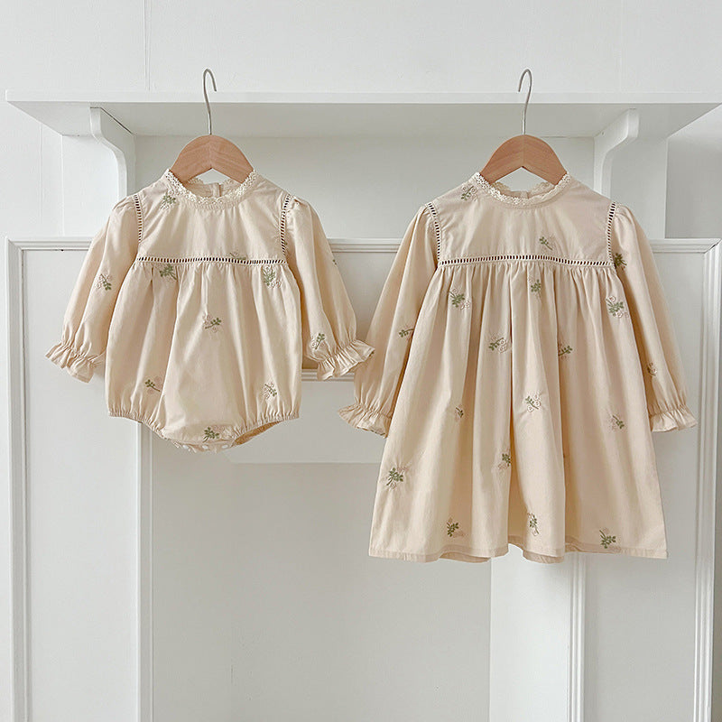 A beautiful baby girls dress featuring floral embroidery and lace trim, available in beige and apricot colors.