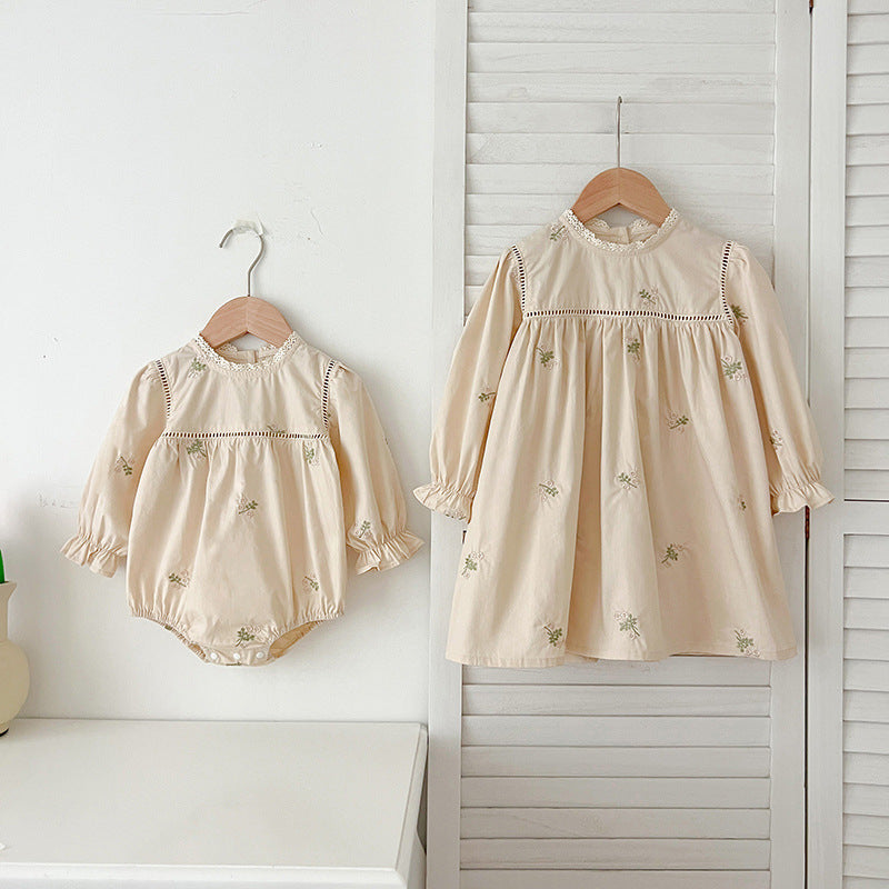 A beautiful baby girls dress featuring floral embroidery and lace trim, available in beige and apricot colors.