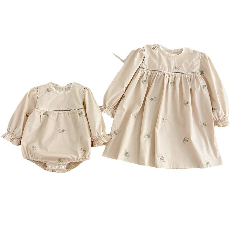 A beautiful baby girls dress featuring floral embroidery and lace trim, available in beige and apricot colors.