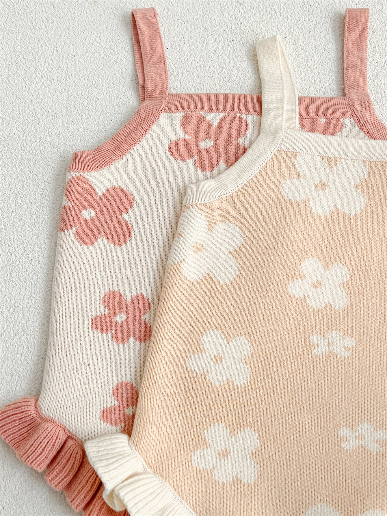 A cute summer dress for baby girls featuring a floral pattern, sleeveless design, available in pink and beige colors.