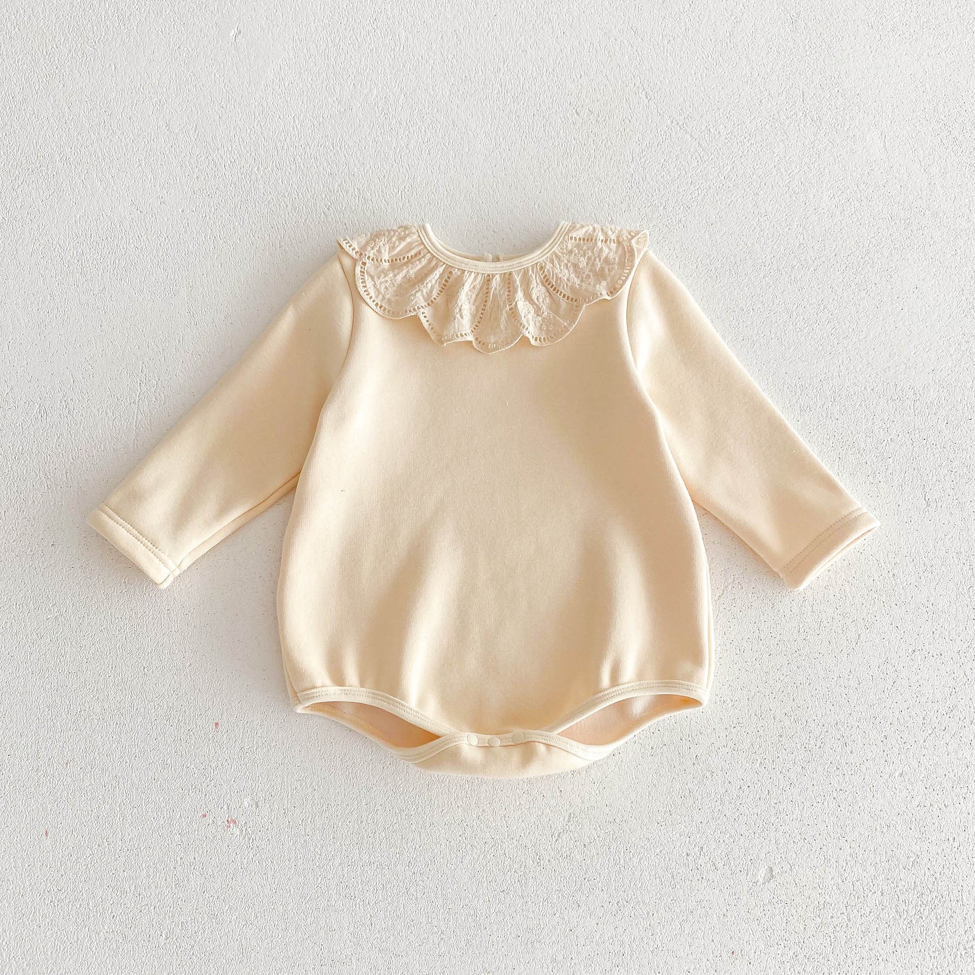 Newborn baby girl wearing a solid beige crew neck long sleeve dress with lace collar, showcasing comfort and style.