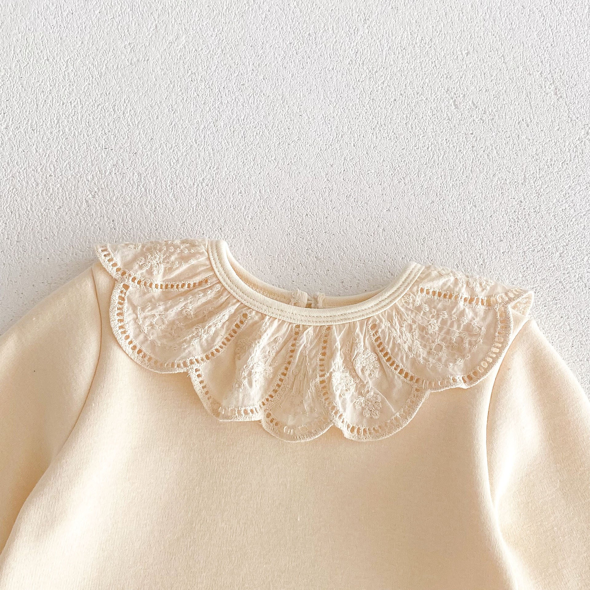 Newborn baby girl wearing a solid beige crew neck long sleeve dress with lace collar, showcasing comfort and style.