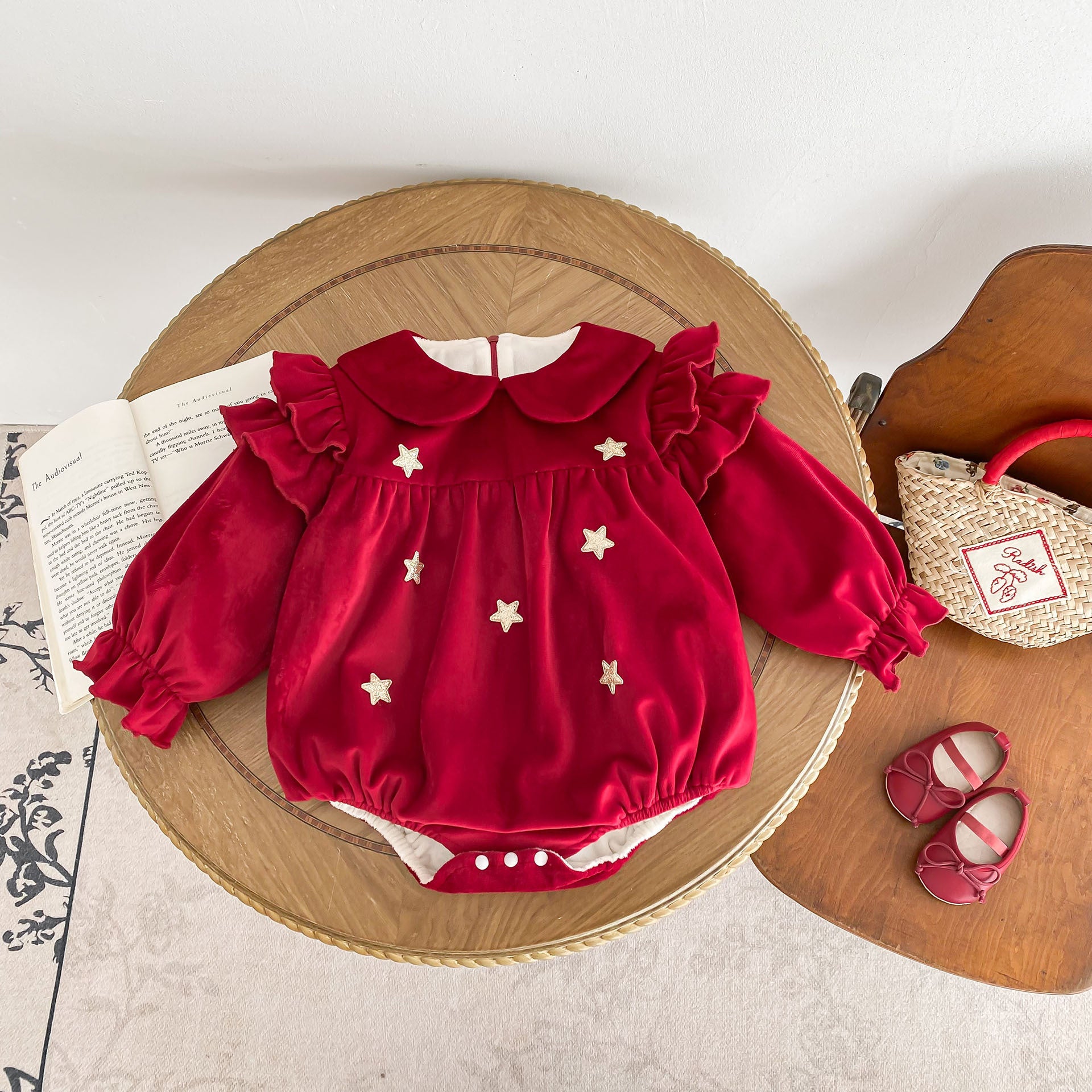 Newborn baby girl wearing a red Peter Pan collar dress with long ruffle sleeves, showcasing a stylish and comfortable design.