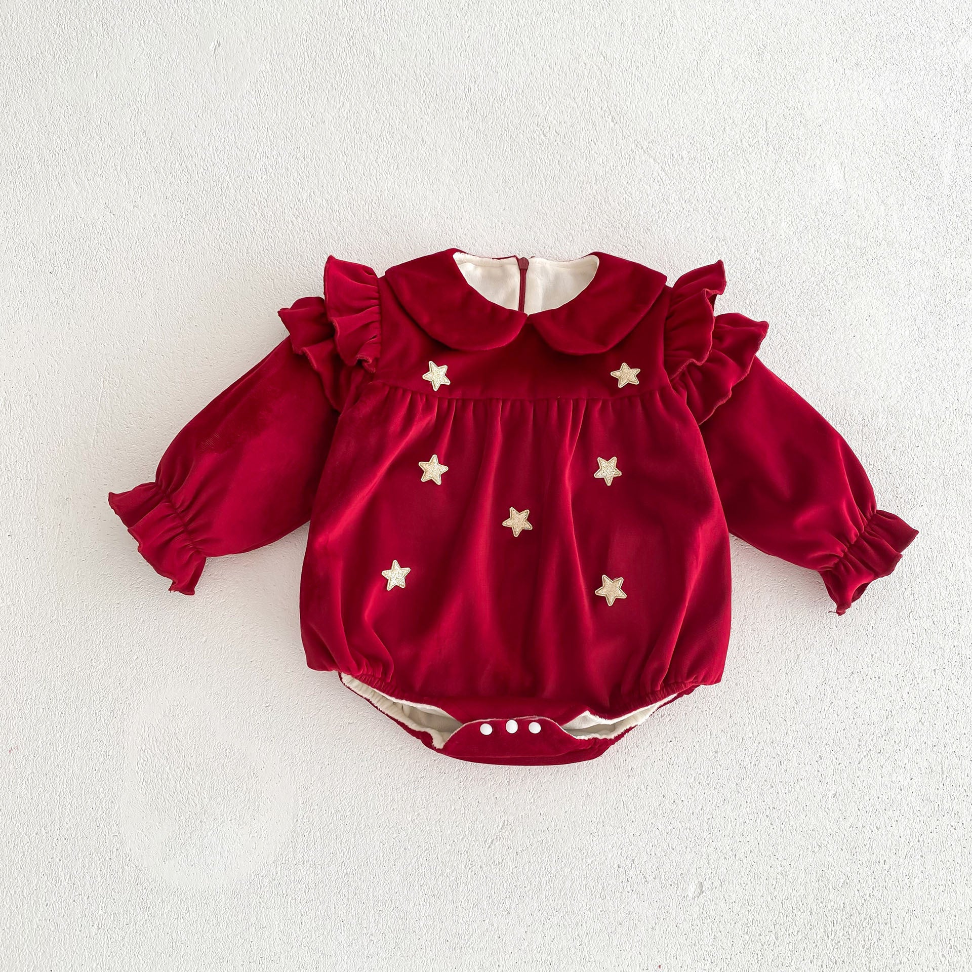 Newborn baby girl wearing a red Peter Pan collar dress with long ruffle sleeves, showcasing a stylish and comfortable design.