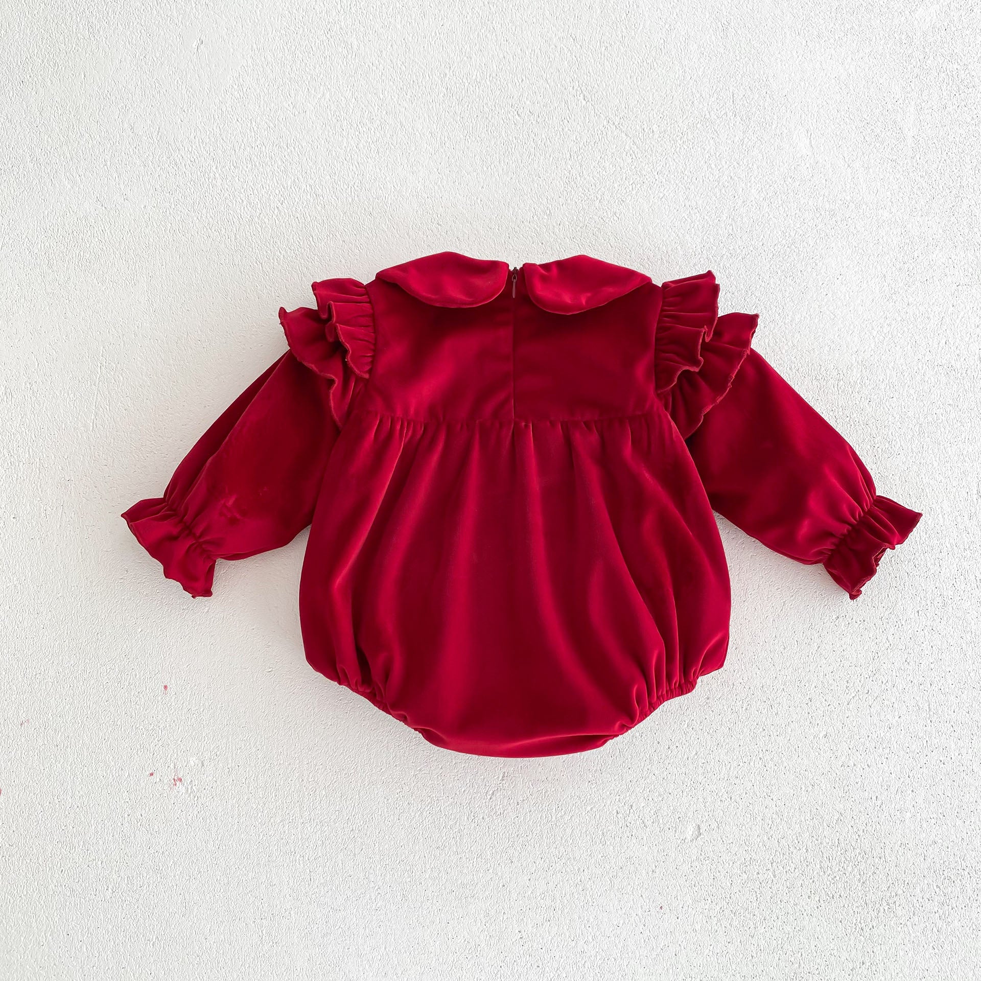 Newborn baby girl wearing a red Peter Pan collar dress with long ruffle sleeves, showcasing a stylish and comfortable design.