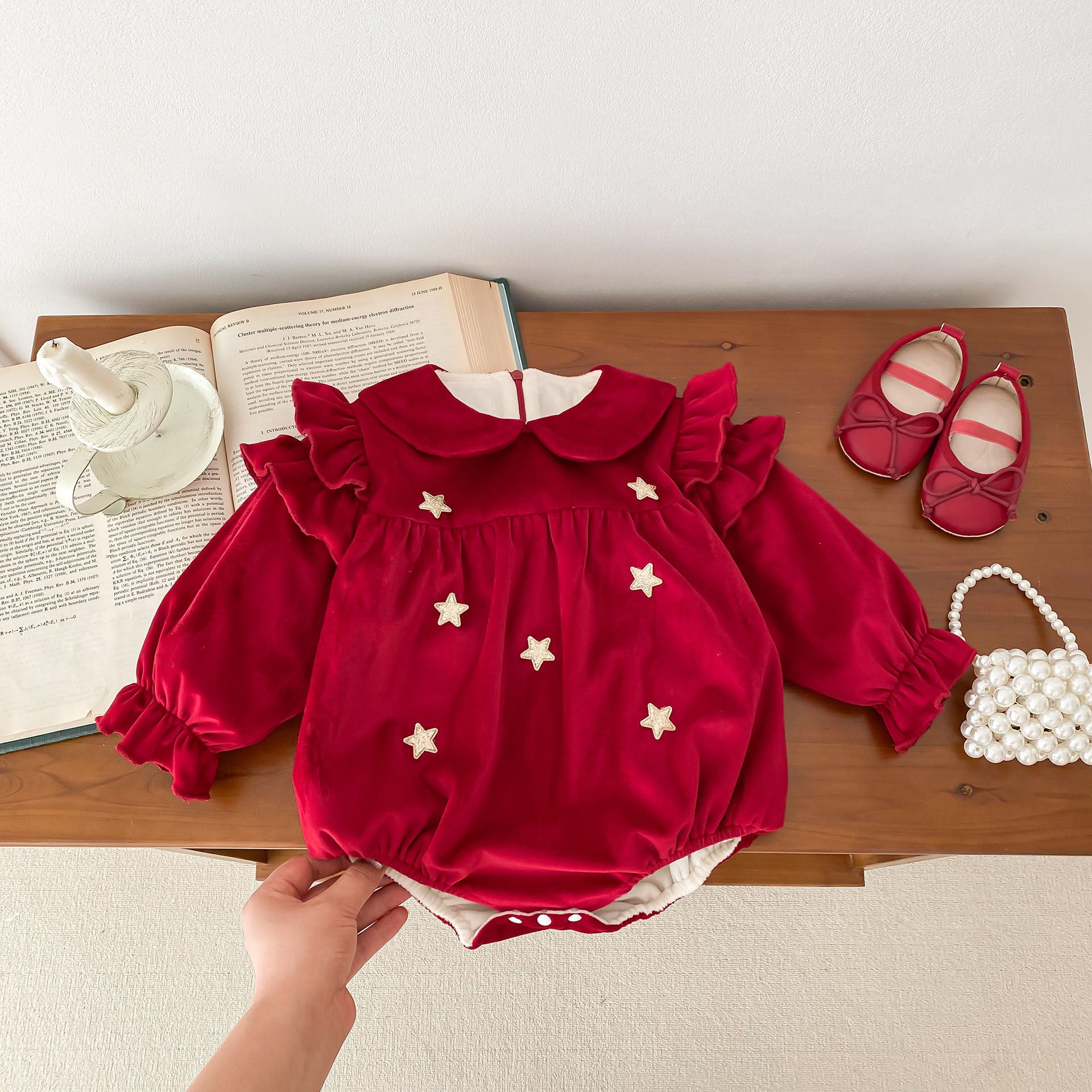 Newborn baby girl wearing a red Peter Pan collar dress with long ruffle sleeves, showcasing a stylish and comfortable design.