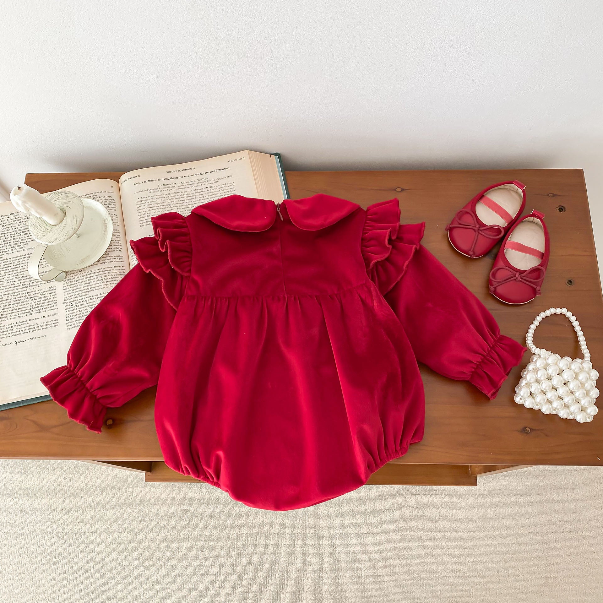 Newborn baby girl wearing a red Peter Pan collar dress with long ruffle sleeves, showcasing a stylish and comfortable design.