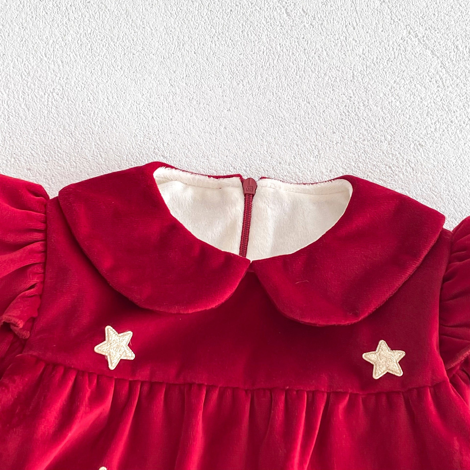 Newborn baby girl wearing a red Peter Pan collar dress with long ruffle sleeves, showcasing a stylish and comfortable design.