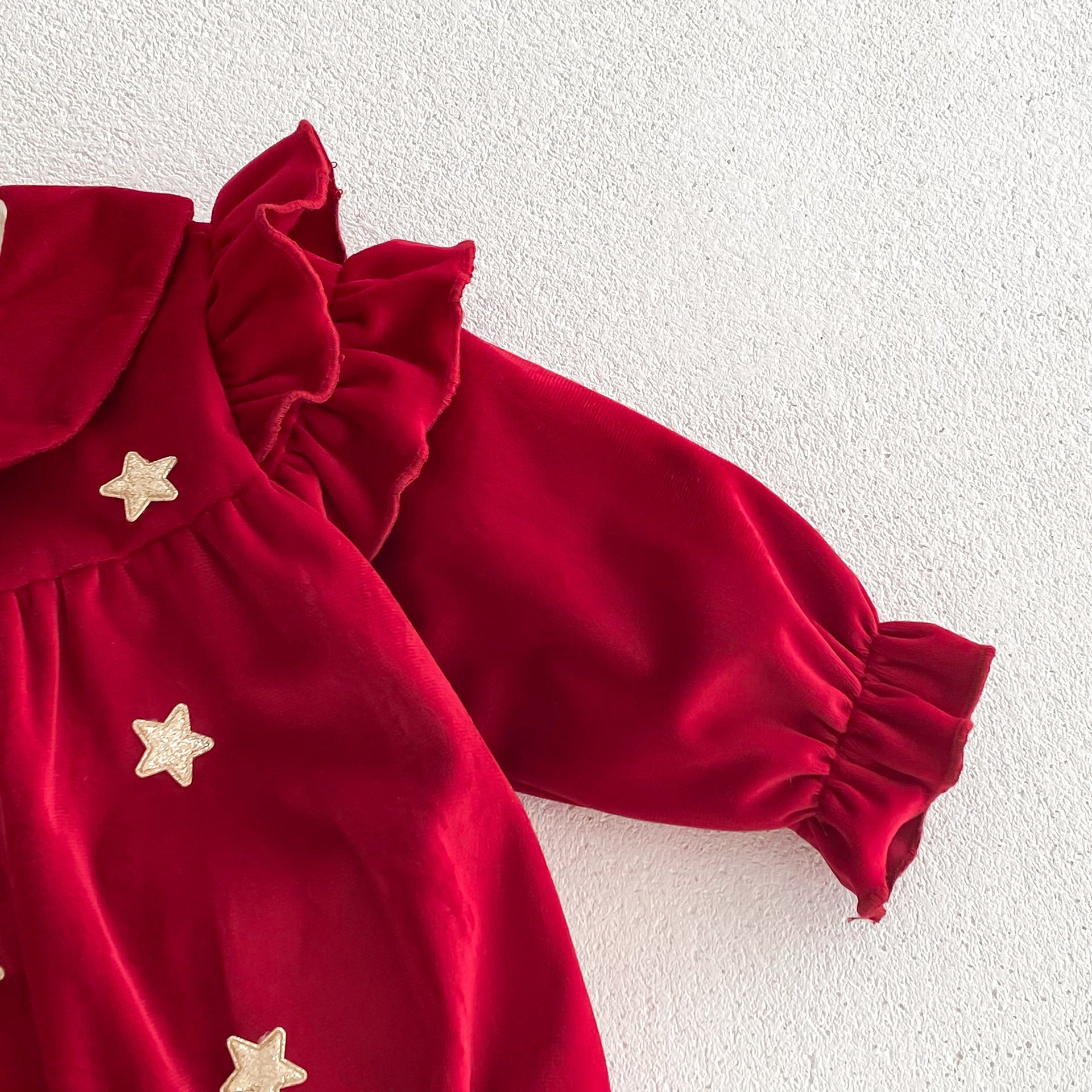 Newborn baby girl wearing a red Peter Pan collar dress with long ruffle sleeves, showcasing a stylish and comfortable design.