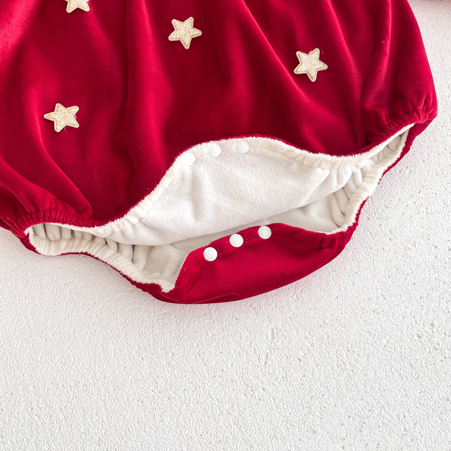 Newborn baby girl wearing a red Peter Pan collar dress with long ruffle sleeves, showcasing a stylish and comfortable design.