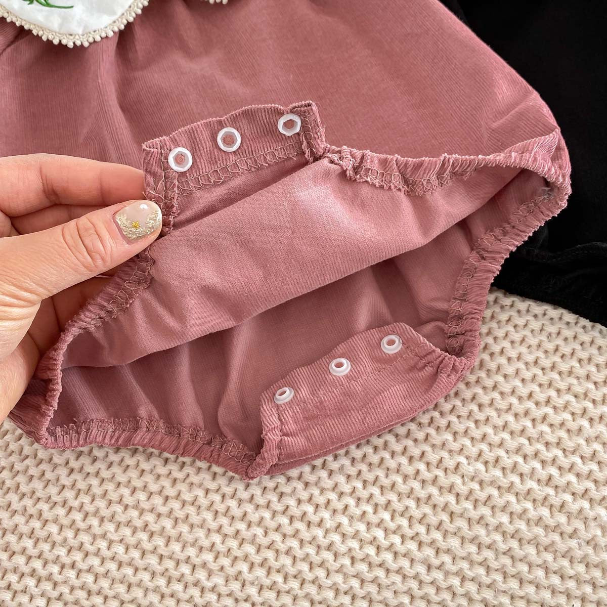 Newborn baby girl wearing a stylish Peter Pan floral collar long sleeves outfit in black and pink, showcasing a charming design.