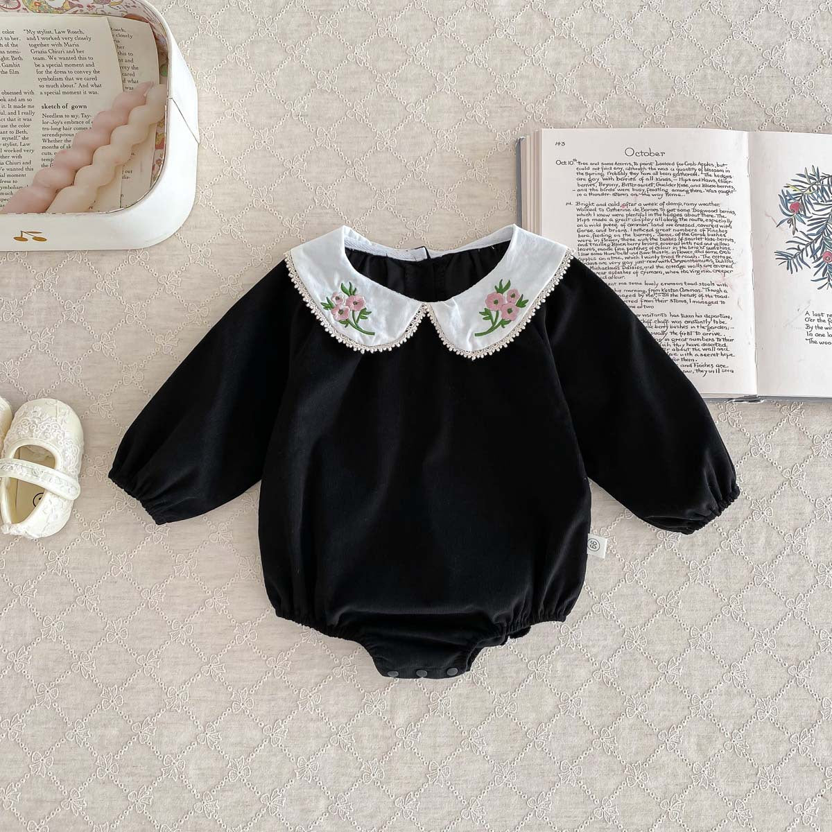 Newborn baby girl wearing a stylish Peter Pan floral collar long sleeves outfit in black and pink, showcasing a charming design.