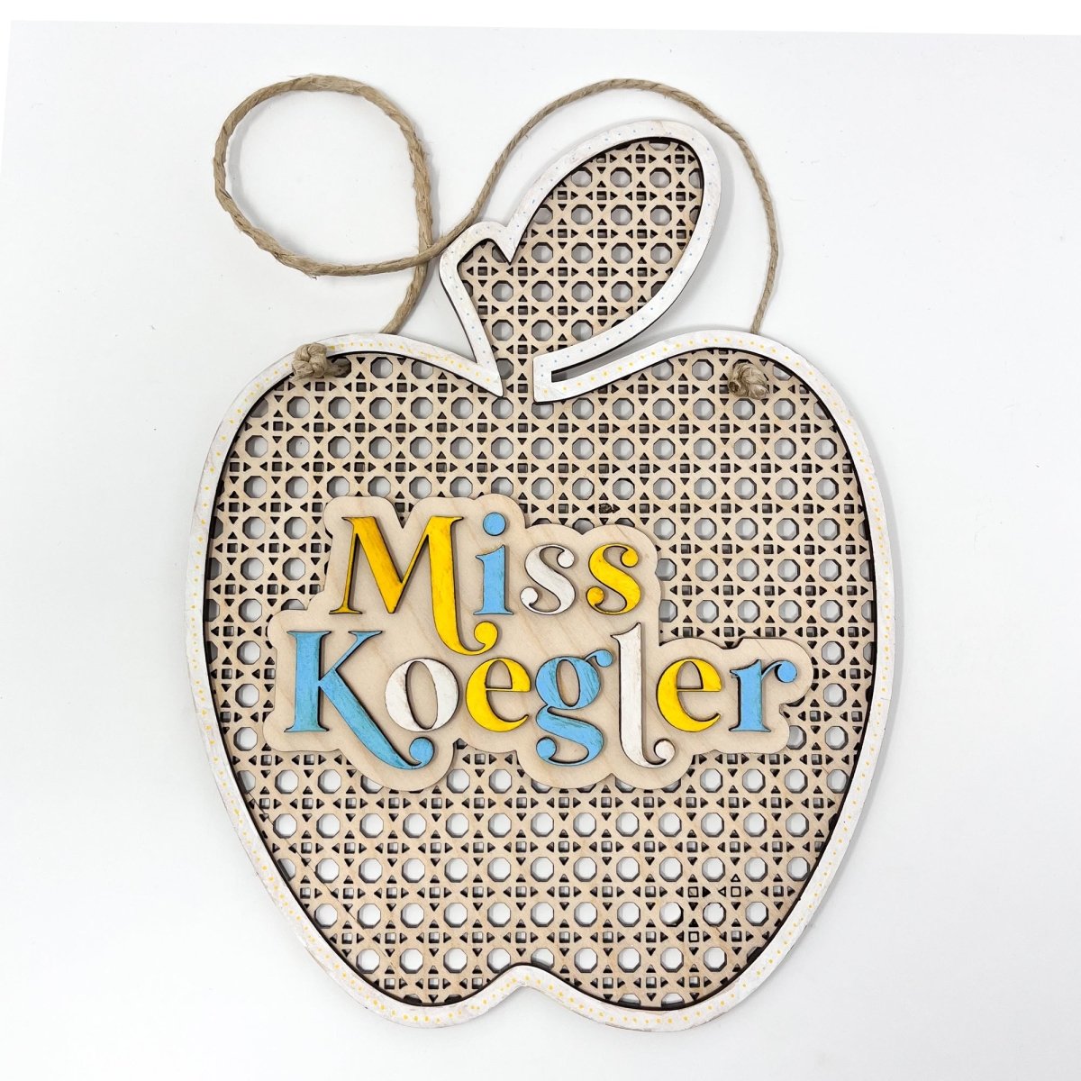 A personalized rattan apple sign for teachers, featuring raised lettering and colorful design, ready to hang with jute rope.