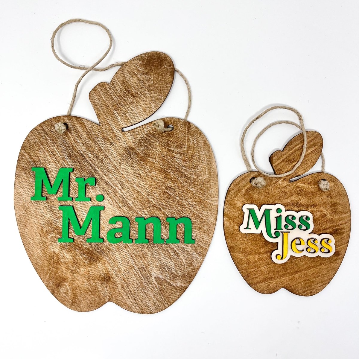 A personalized teacher apple sign made of natural wood, featuring raised lettering and colorful design, ready to hang with jute rope.