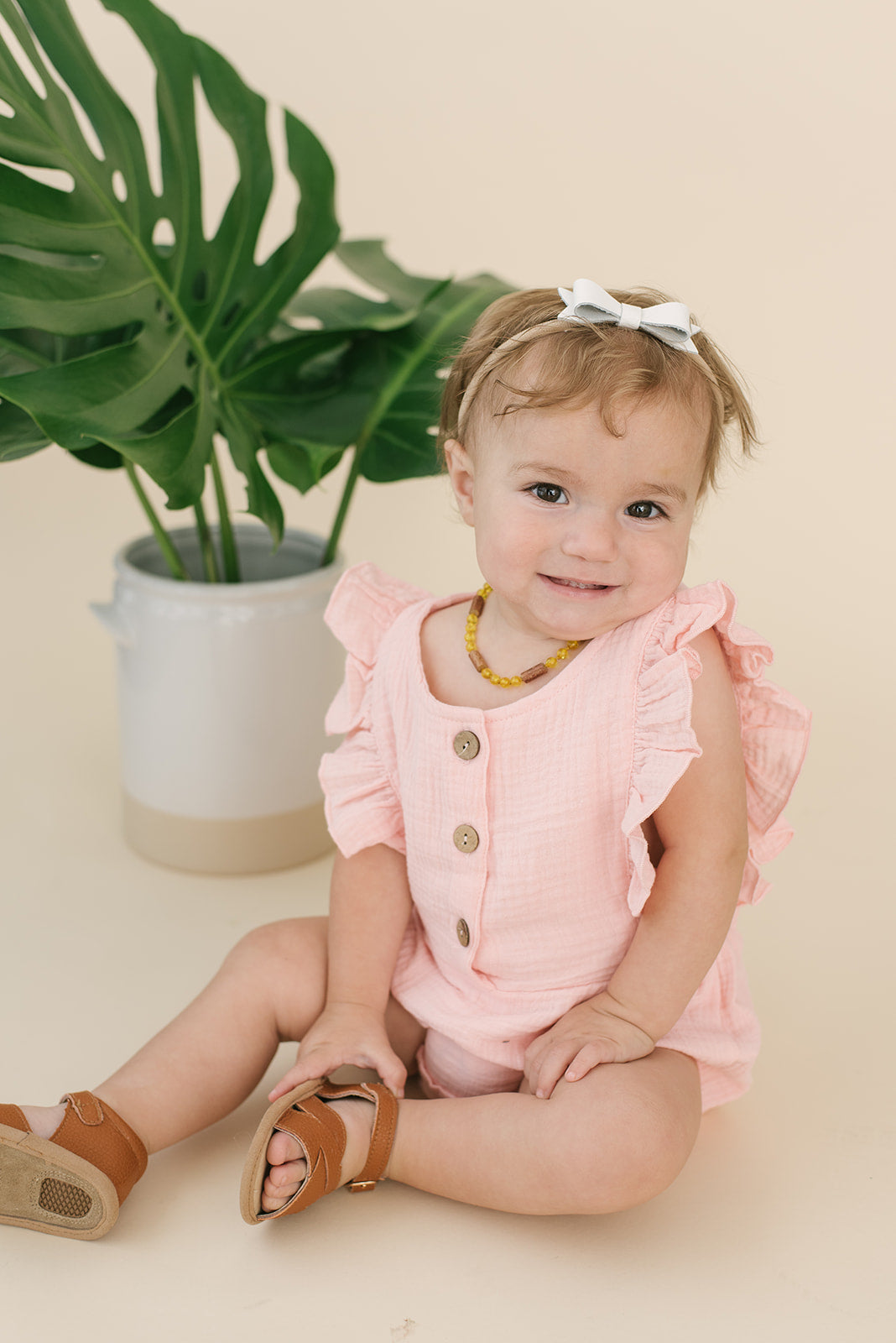 A cute pink summer romper made of soft linen, featuring diaper snaps and a stylish design for babies.