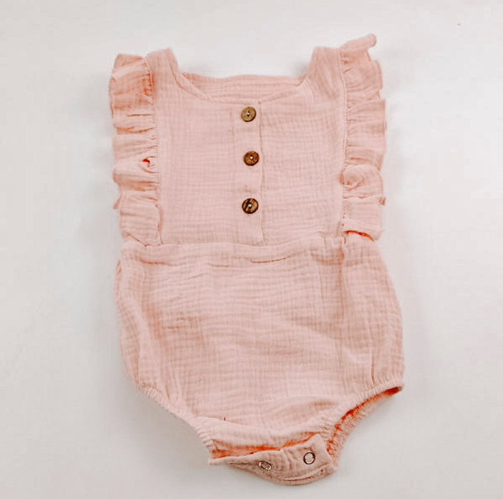 A cute pink summer romper made of soft linen, featuring diaper snaps and a stylish design for babies.