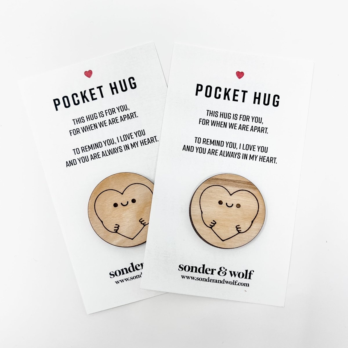 A wooden hug token with an engraved heart, accompanied by a card, symbolizing love and connection.