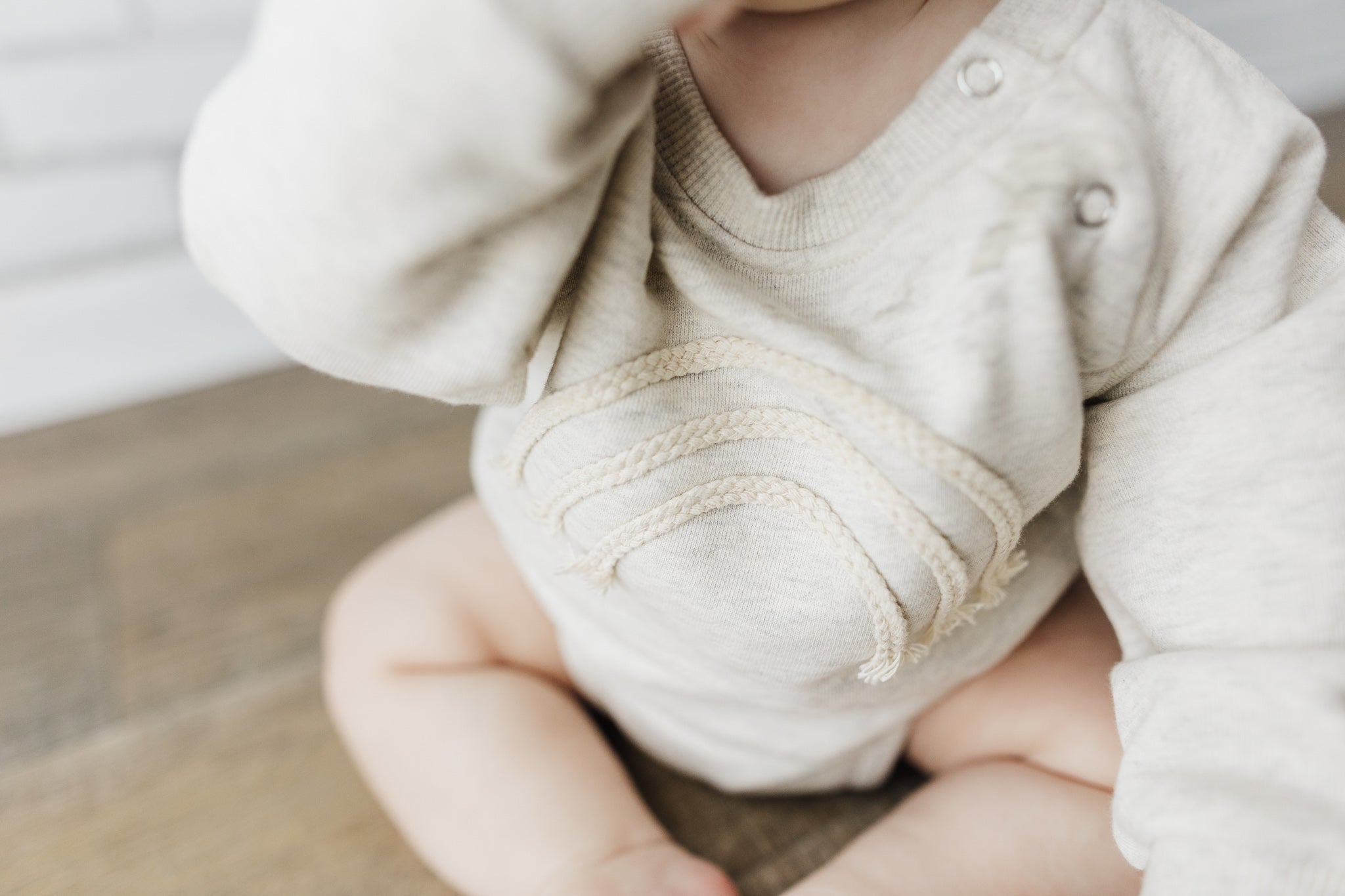 A soft and lightweight Rainbow Baby Bodysuit in grey and green, perfect for infants.