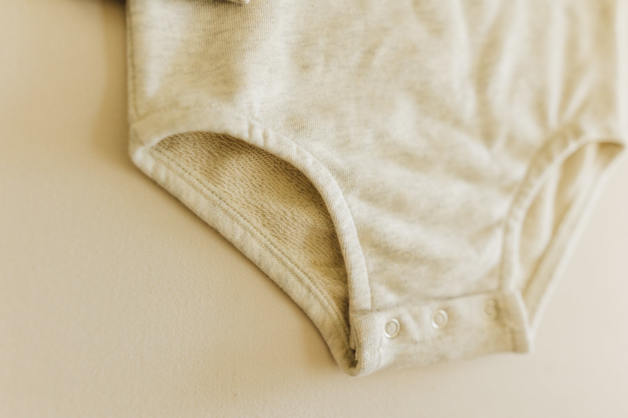 A soft and lightweight Rainbow Baby Bodysuit in grey and green, perfect for infants.