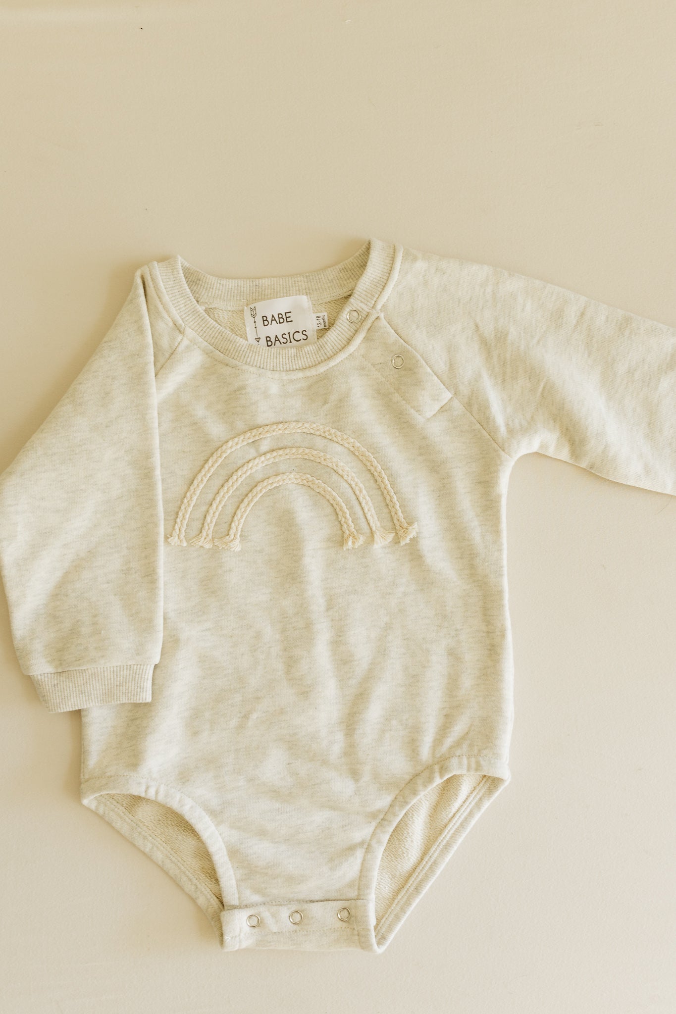 A soft and lightweight Rainbow Baby Bodysuit in grey and green, perfect for infants.