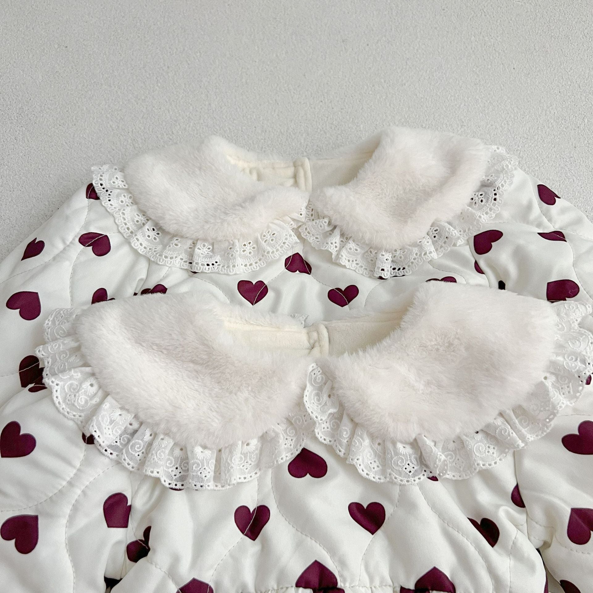 A beautiful long sleeve dress featuring a red heart pattern and a Peter Pan lace collar, perfect for young girls.