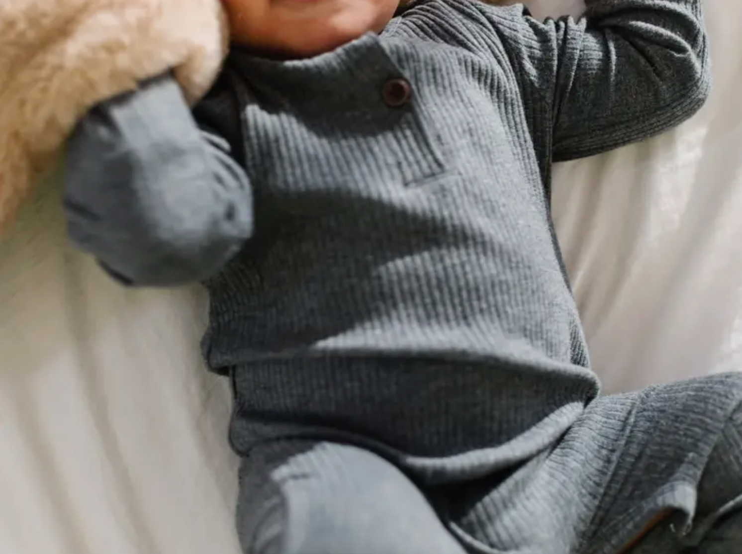 A cozy ribbed baby romper in soft cotton, featuring decorative buttons and snaps, available in four fall colors.