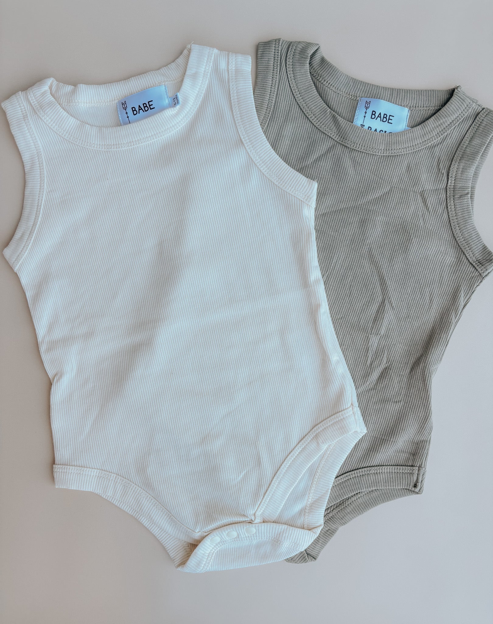 A soft ribbed cotton baby romper in cream and taupe, featuring convenient diaper snaps, perfect for summer outings.