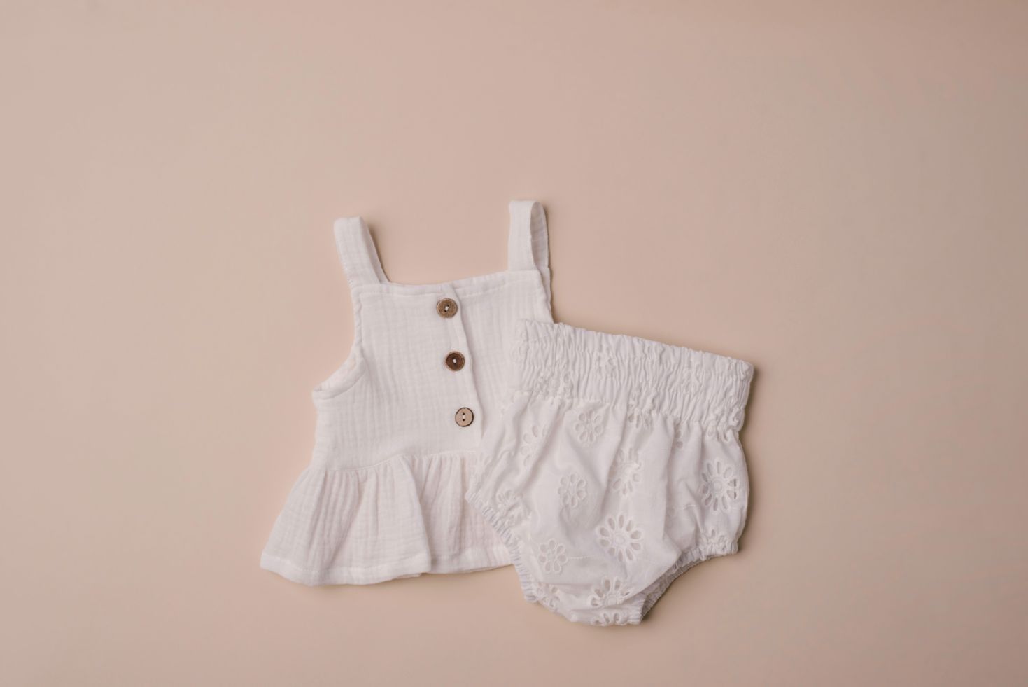 A soft cotton ruffle tank top in beige and white, perfect for layering and comfortable wear for children.