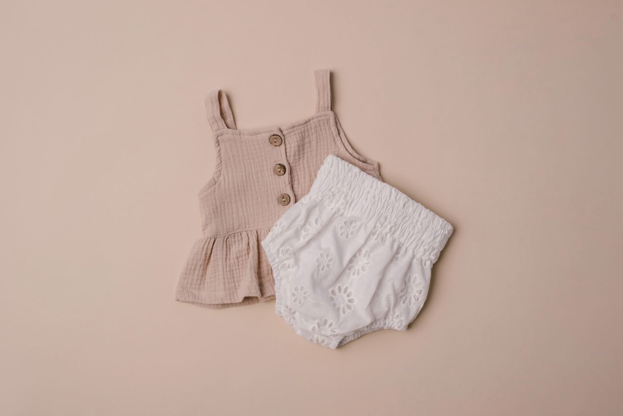 A soft cotton ruffle tank top in beige and white, perfect for layering and comfortable wear for children.