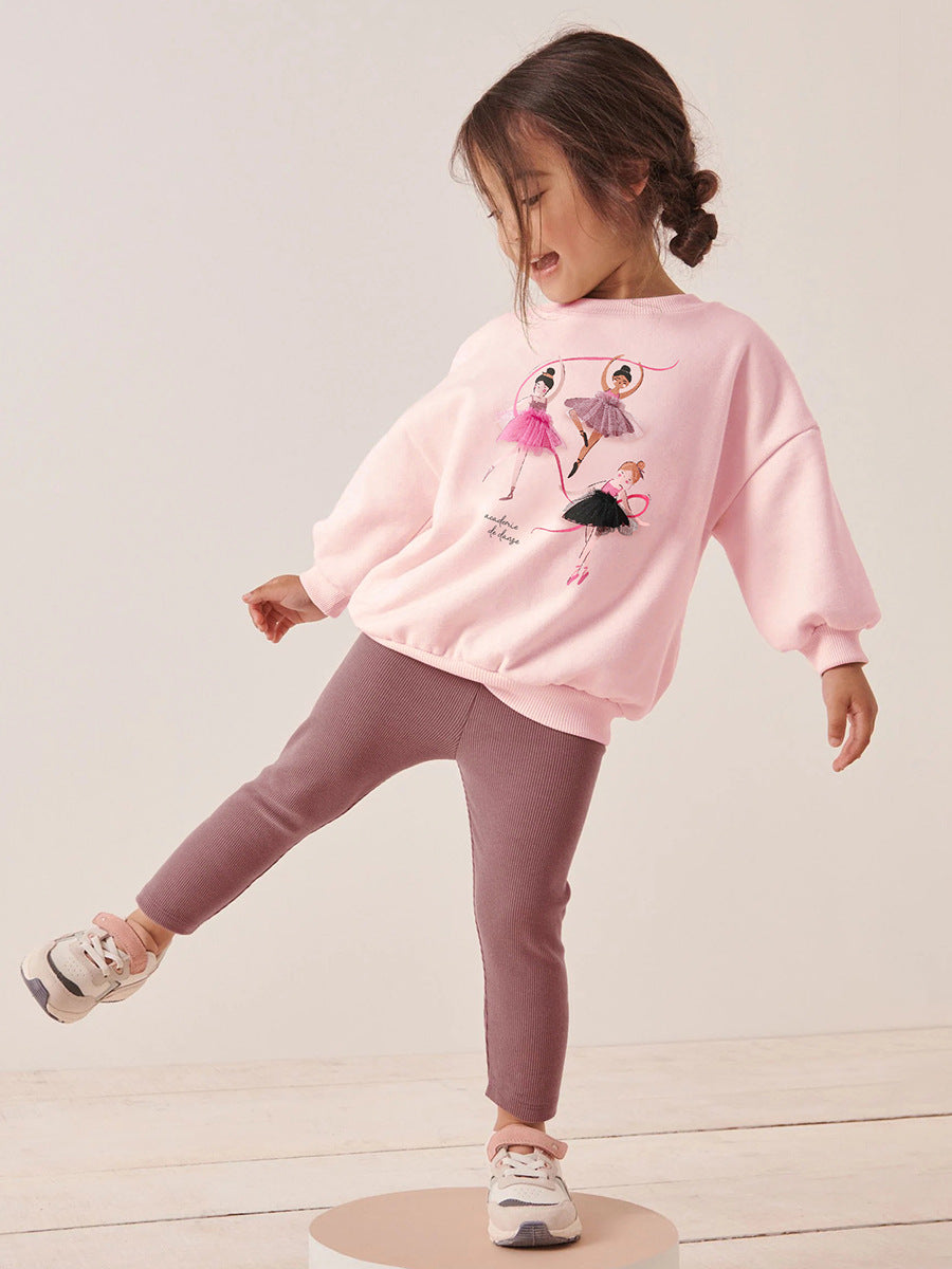 A pink long sleeve crew neck top featuring a cartoon dancer pattern, designed for girls aged 12 months to 10 years.