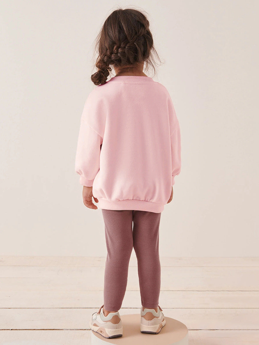 A pink long sleeve crew neck top featuring a cartoon dancer pattern, designed for girls aged 12 months to 10 years.