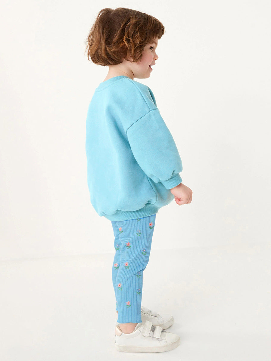 A blue long-sleeve top for girls featuring a colorful cartoon flowers pattern, made from cotton and polyester, perfect for spring and autumn wear.