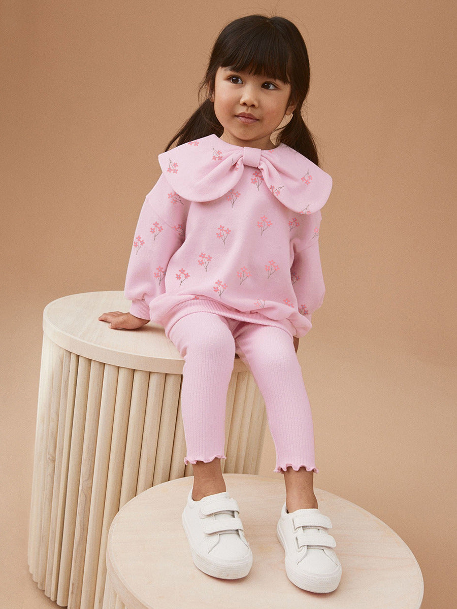 A cute pink long-sleeve top for girls featuring a floral print and bow-shaped detail, perfect for spring and autumn wear.