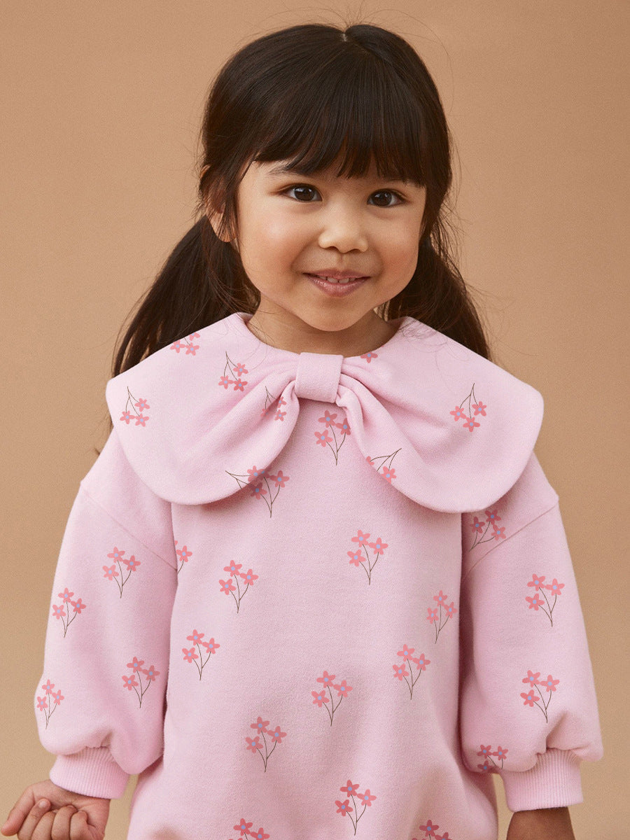 A cute pink long-sleeve top for girls featuring a floral print and bow-shaped detail, perfect for spring and autumn wear.