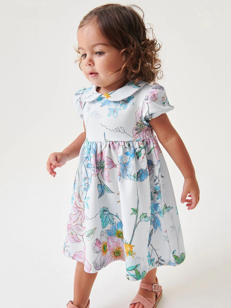 A beautiful white floral dress for baby girls featuring a Peter Pan collar and short sleeves, perfect for spring and summer wear.