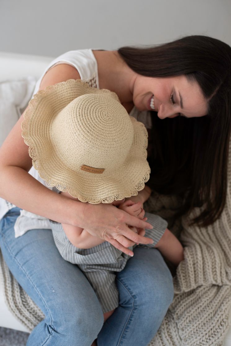 A stylish woven straw baby hat with an adjustable drawstring, perfect for sun protection during outdoor activities.