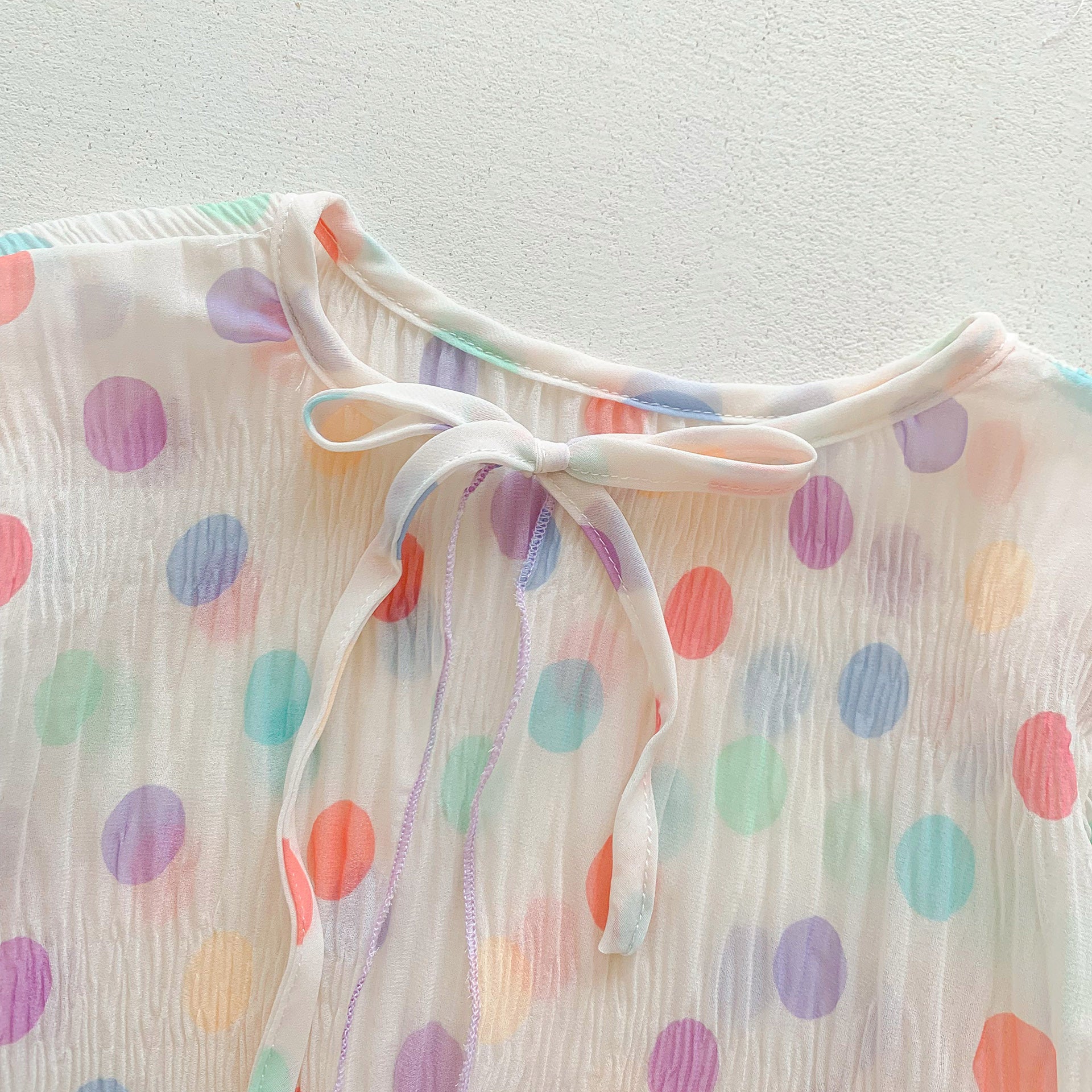 A summer outfit for baby girls featuring colorful polka dots on a beige background, made from breathable cotton.