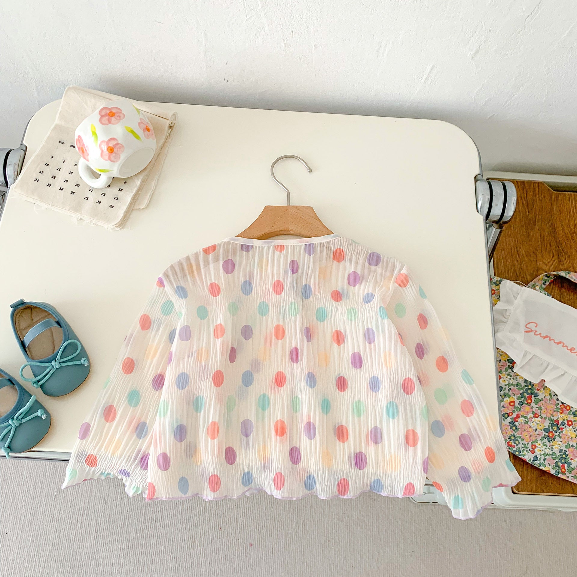 A summer outfit for baby girls featuring colorful polka dots on a beige background, made from breathable cotton.