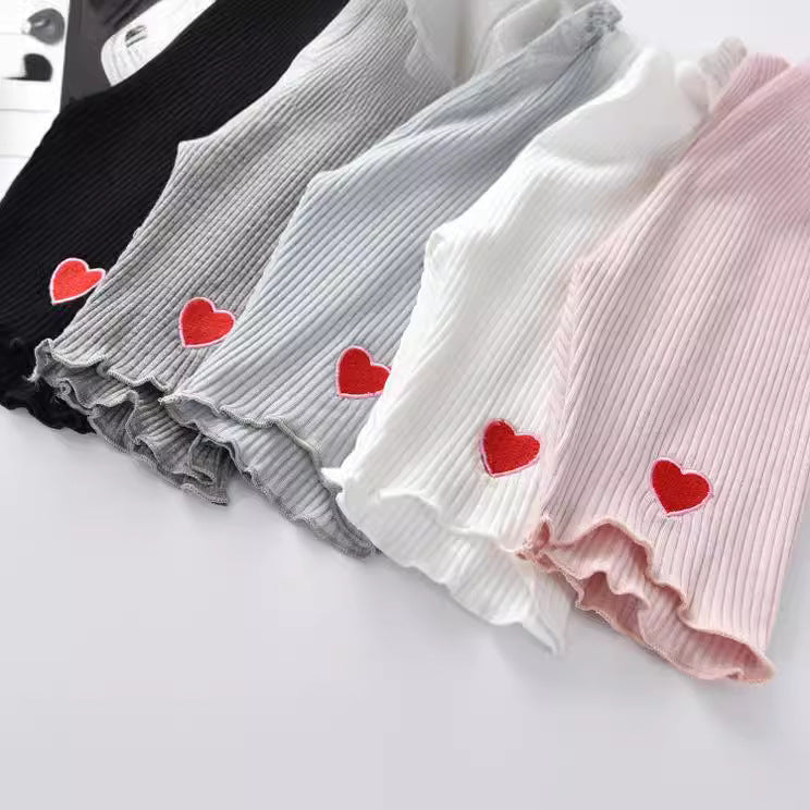 A collection of summer outfits for baby girls featuring heart patterns in various colors including white, black, pink, blue, and grey.