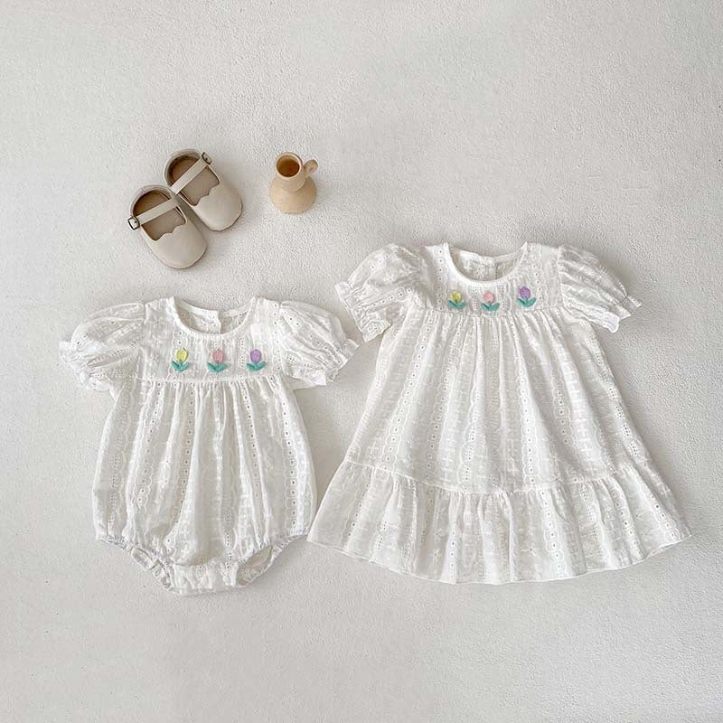 A cute summer dress for baby girls featuring floral embroidery and hollow-out short sleeves, made from soft cotton in white.