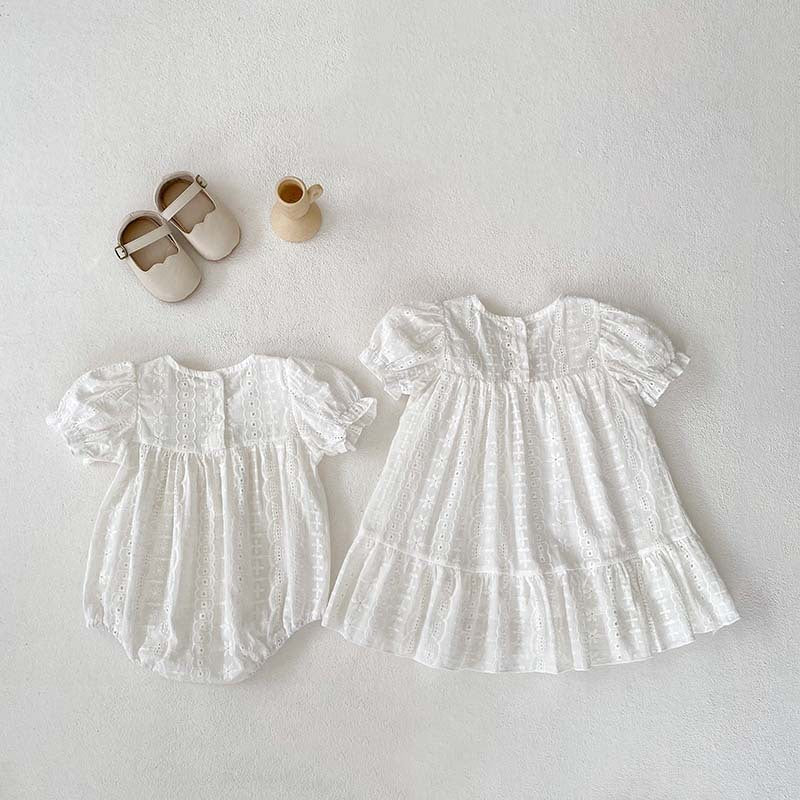 A cute summer dress for baby girls featuring floral embroidery and hollow-out short sleeves, made from soft cotton in white.