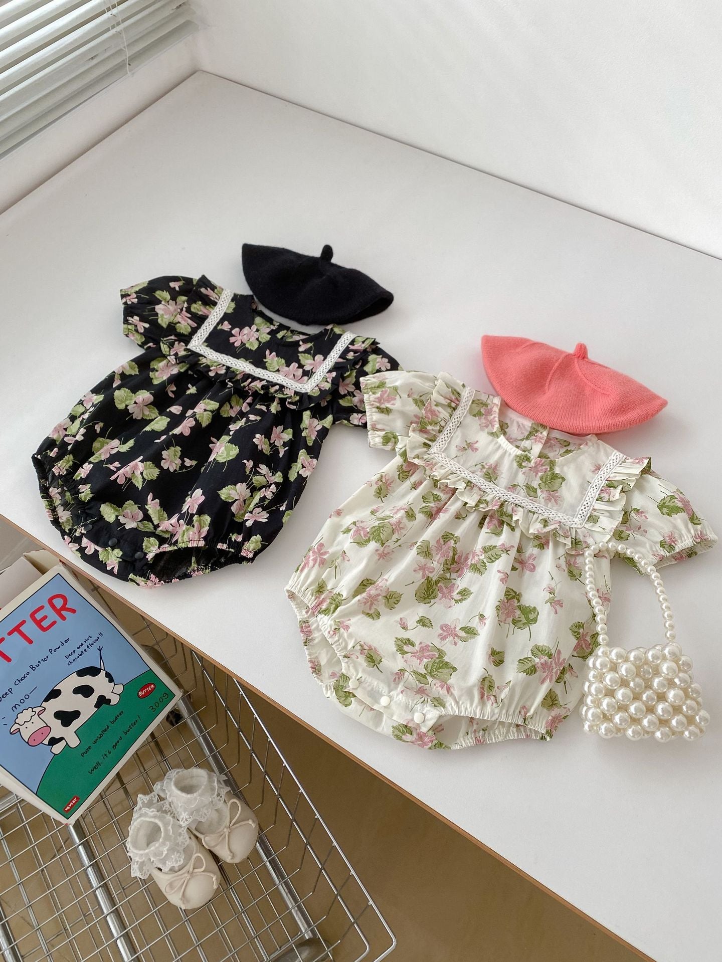 A cute summer dress for baby girls featuring a floral pattern, short sleeves, and available in multiple colors including black, pink, beige, and apricot.