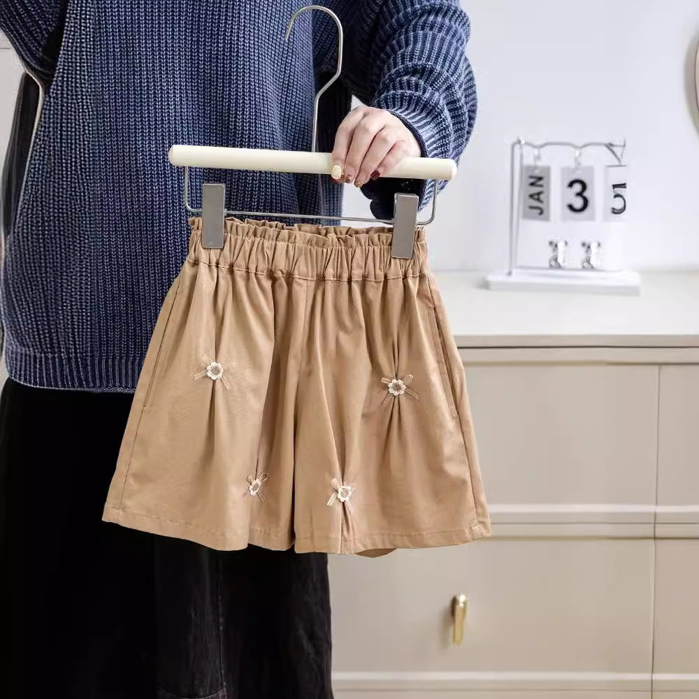 A cute summer pleated skirt for girls featuring a floral pattern and bows, available in pink and coffee colors.